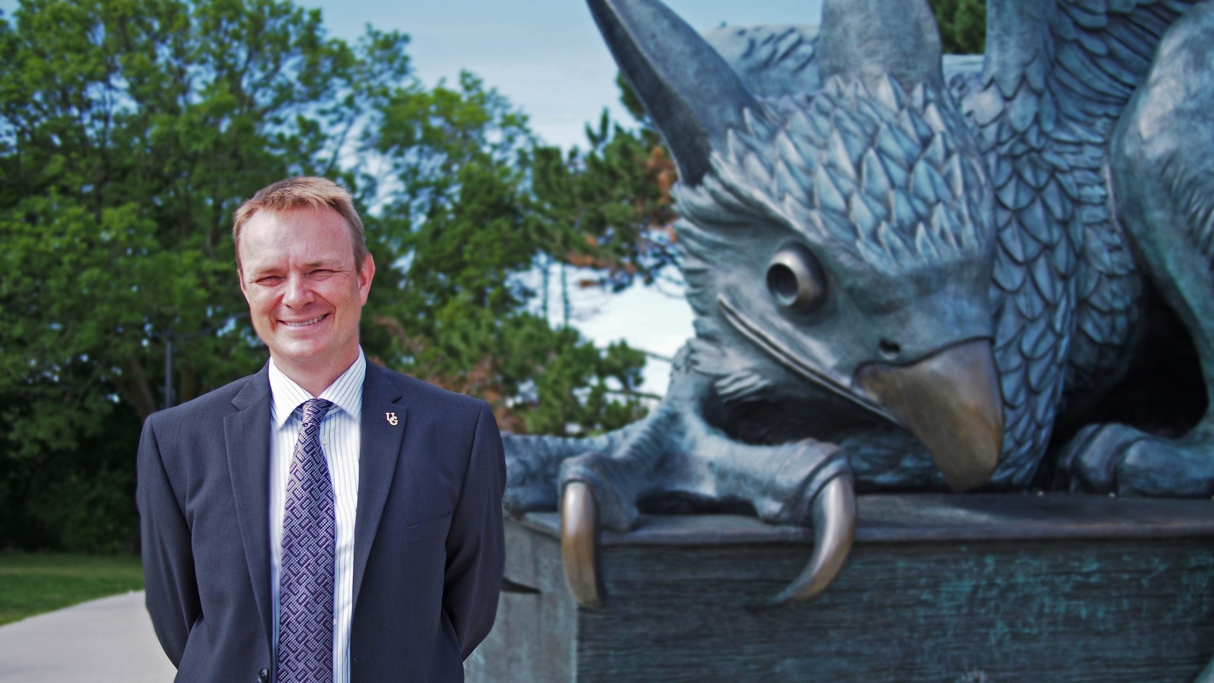 Professor Evan Fraser stands in front of the Gryphon statue