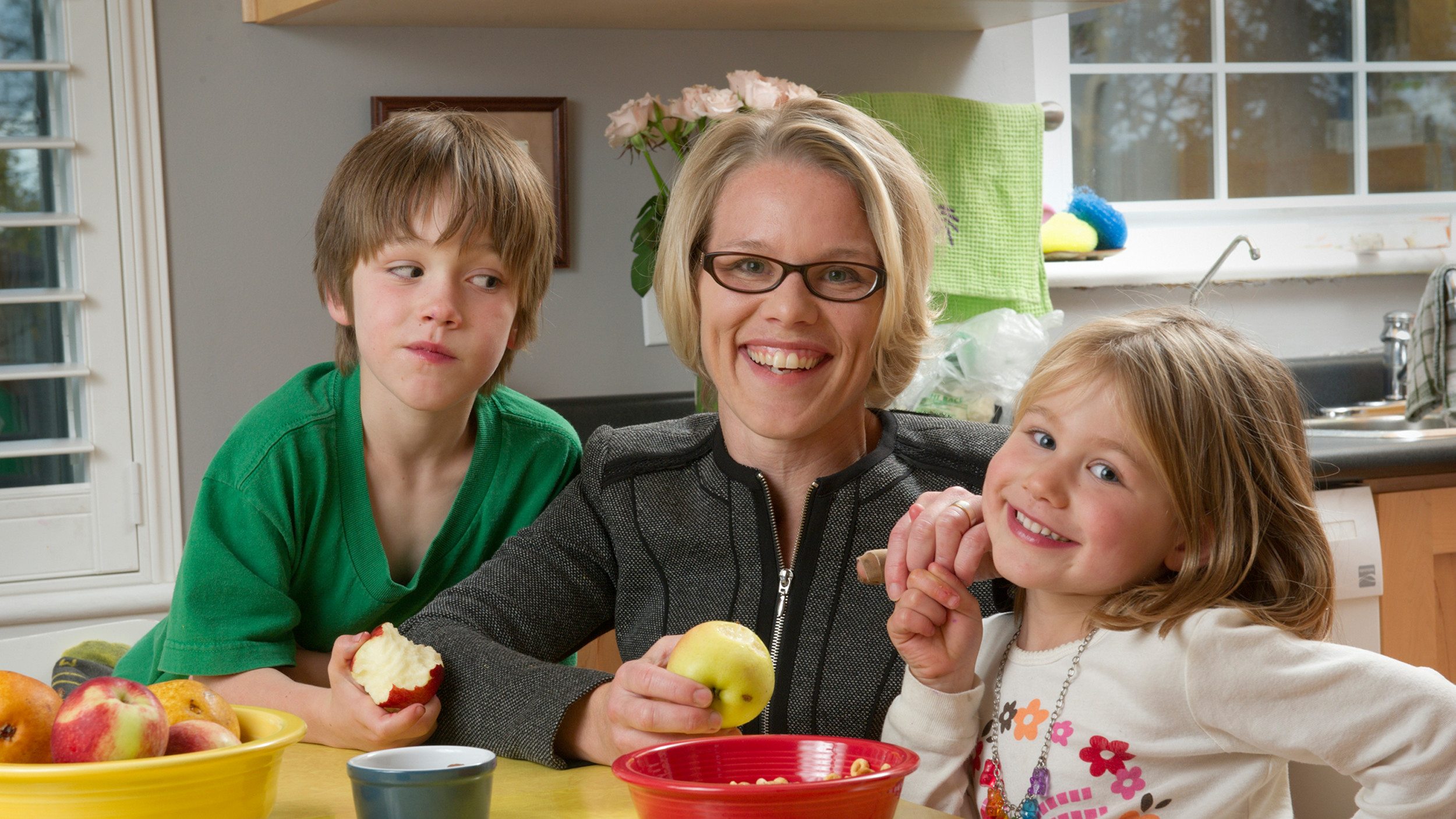 A mother and her children pose at a kitchen table.