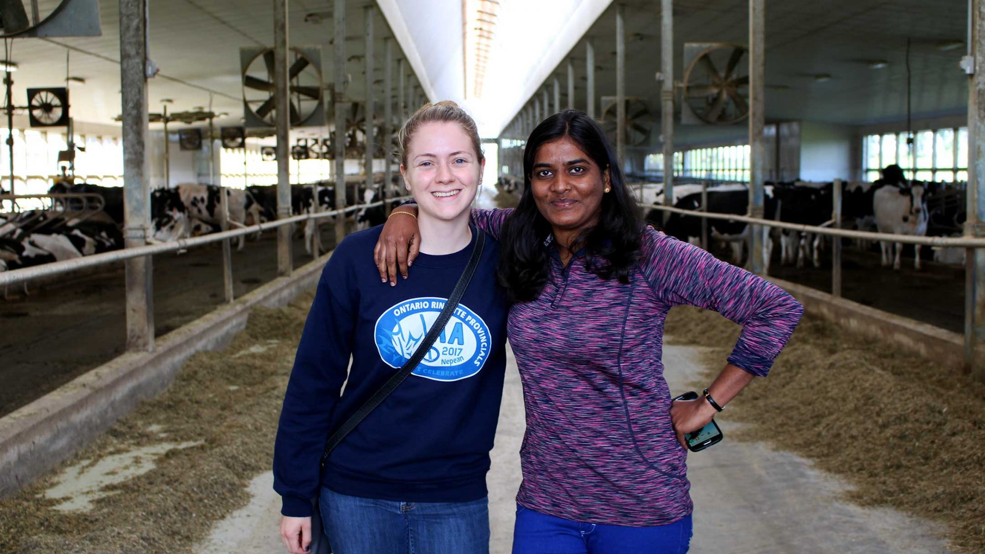 Two graduate students, who have graduate opportunities with Arrell Food Institute and Food from Thought, stand in a dairy barn