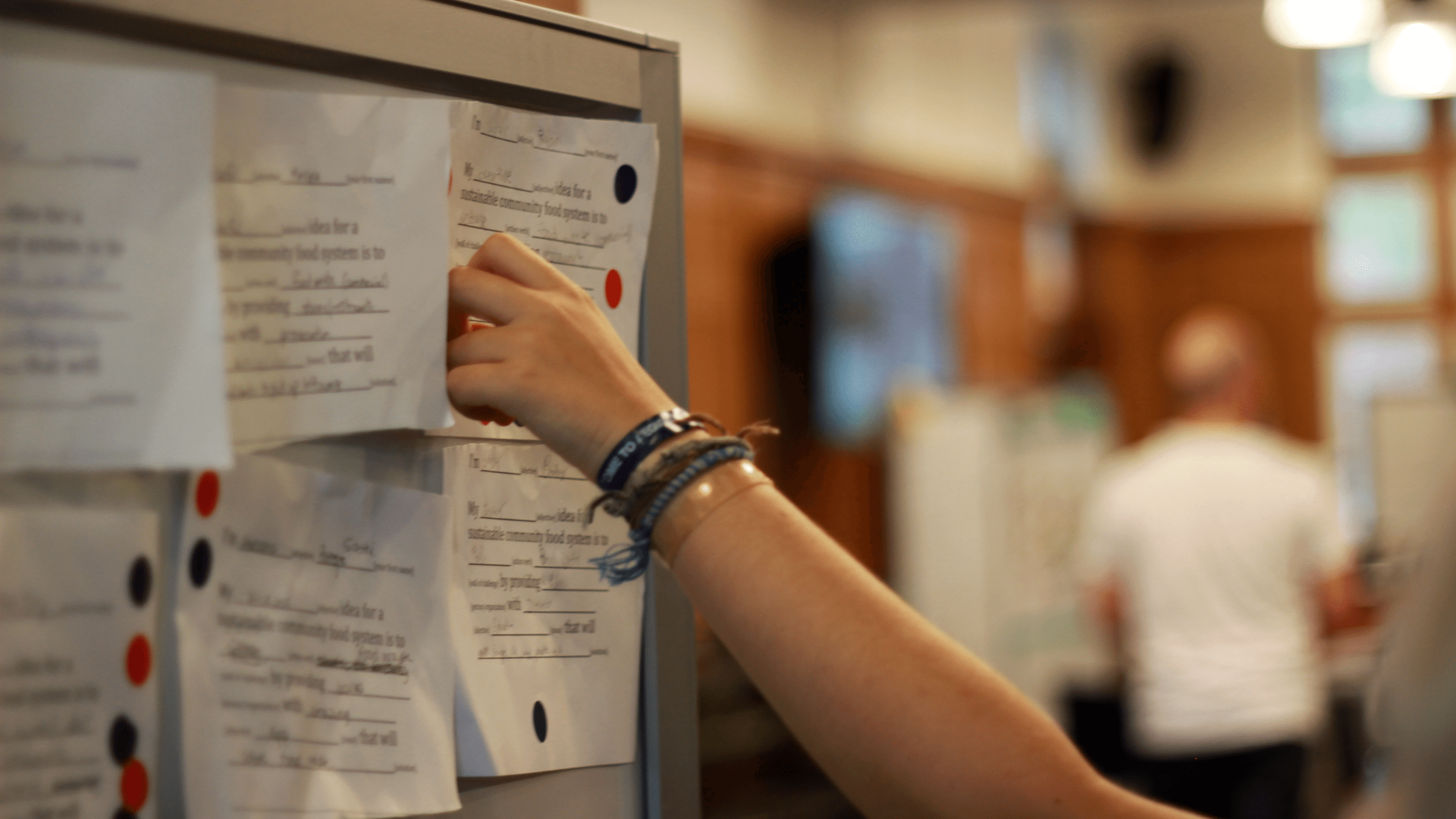 Studen't hand places a sticker onto a paper hung on a board