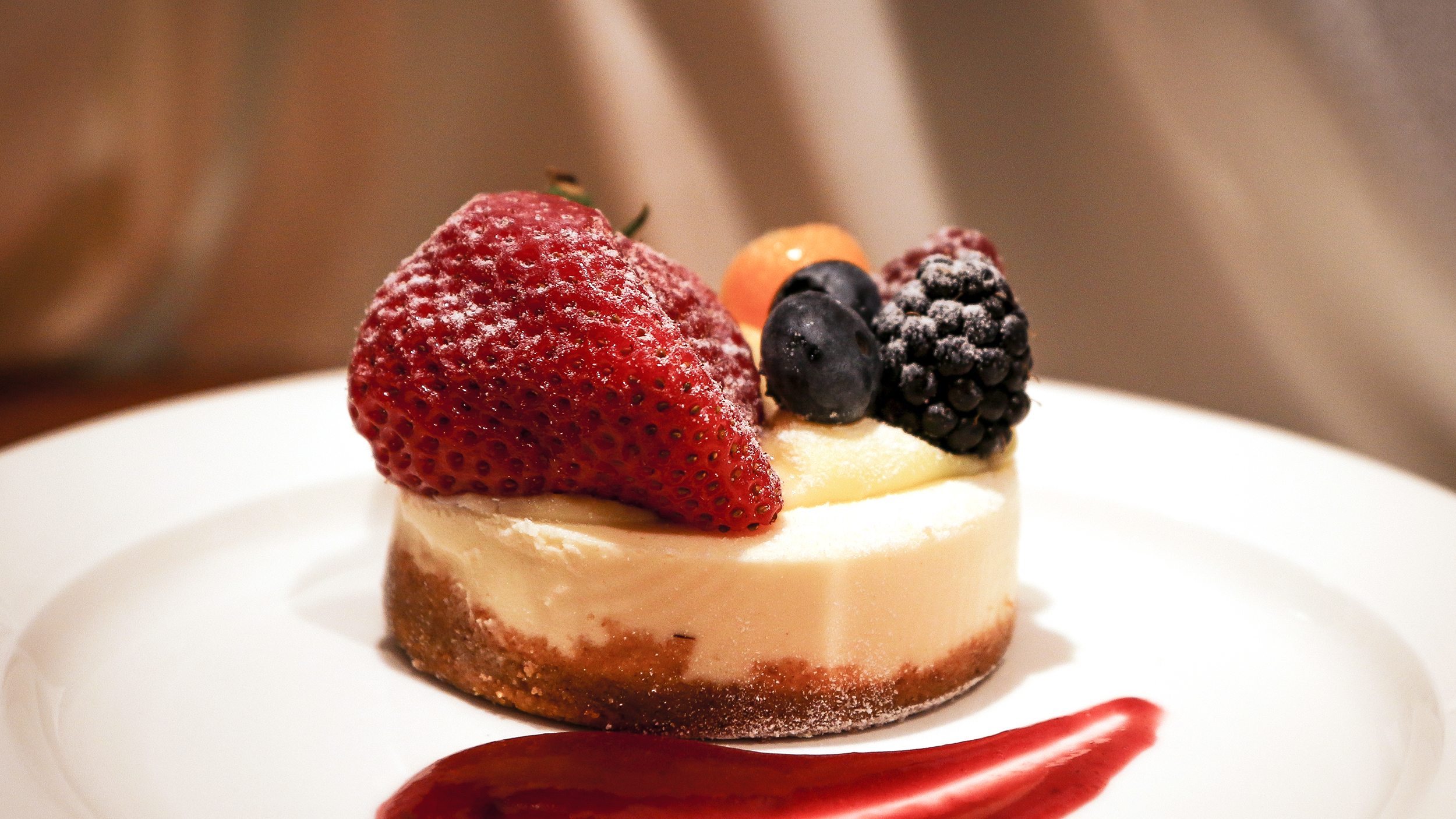 A cheesecake dessert with fruit on a white plate