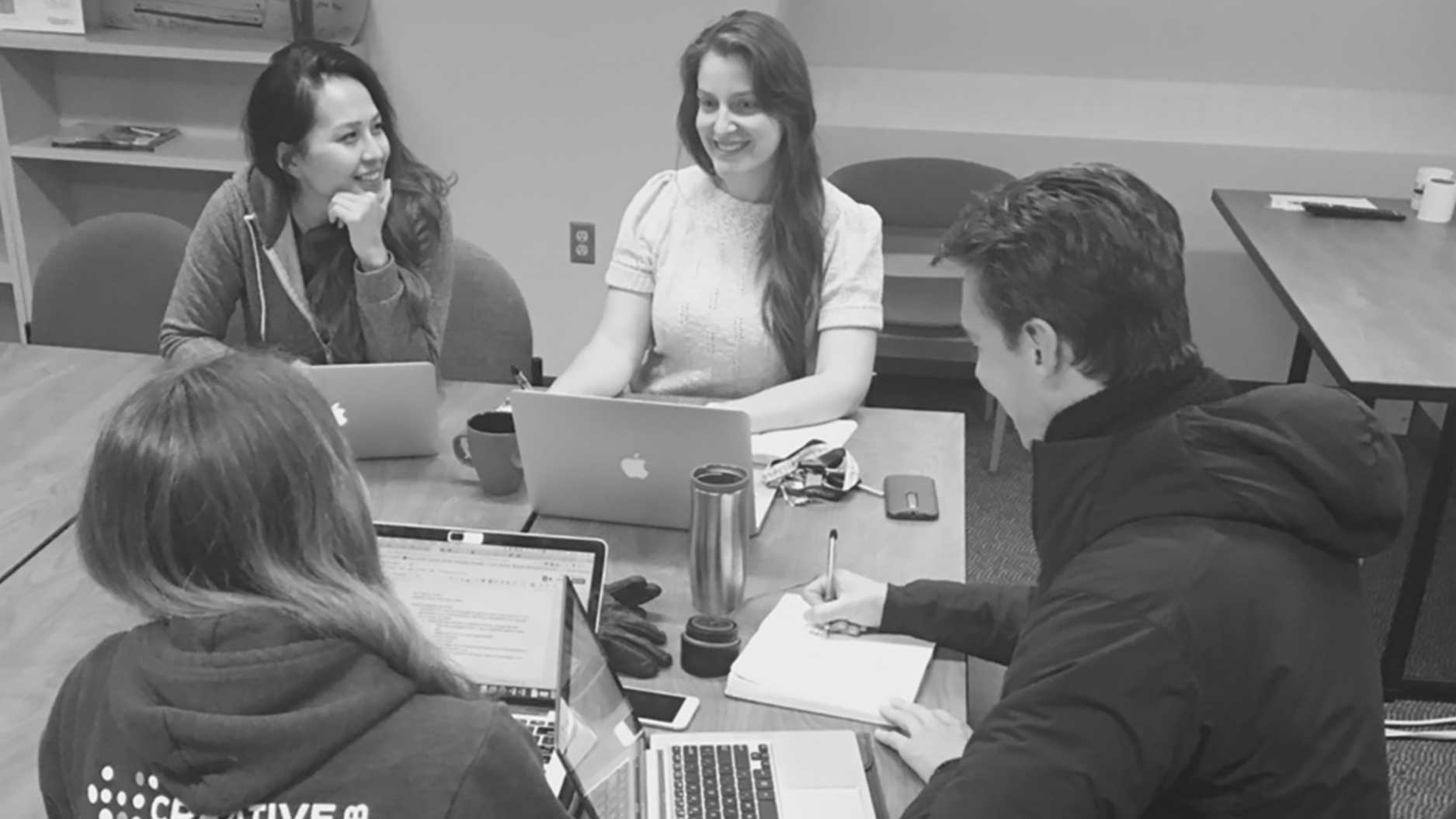 Four graduate students work at a table together on big data projects
