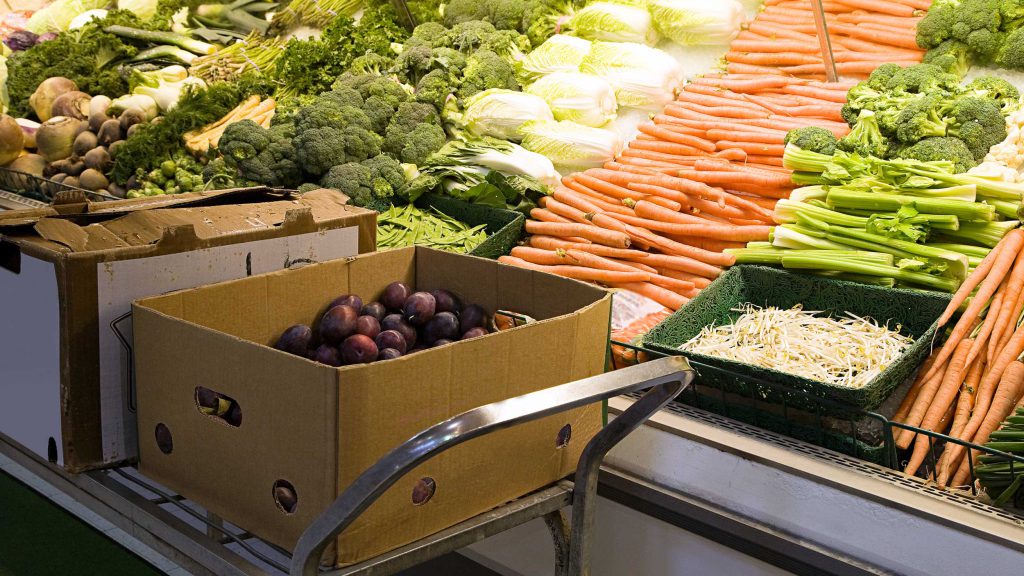 A cart with produce from Canada in boxes sits in front of produce shelves
