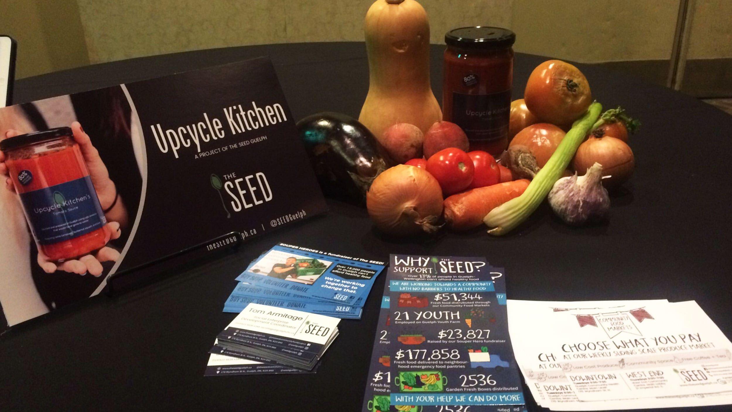 Fliers for the Seed and some vegetables sit on a table
