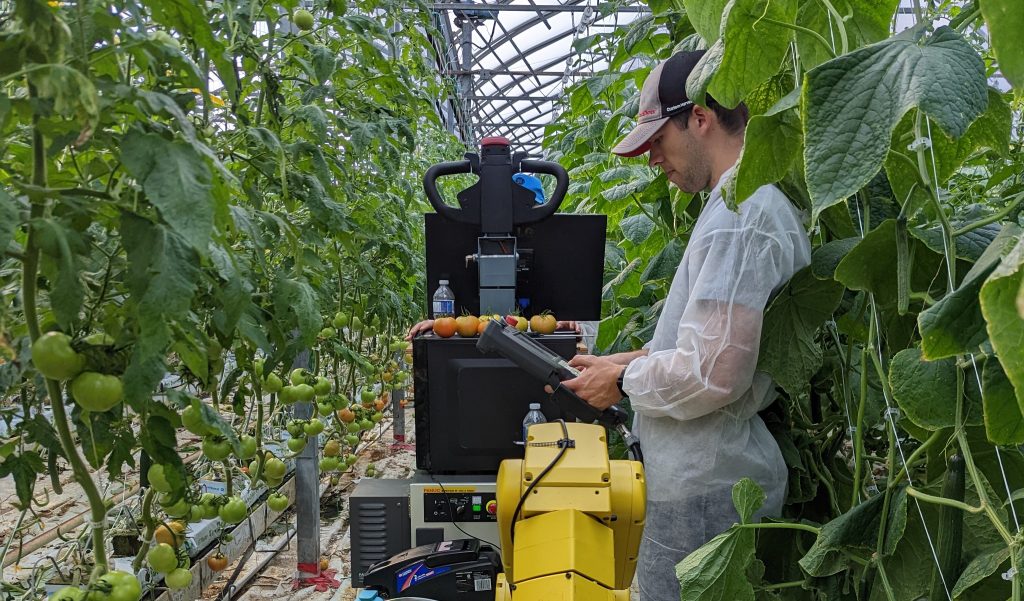 Evan in the greenhouse with a device.