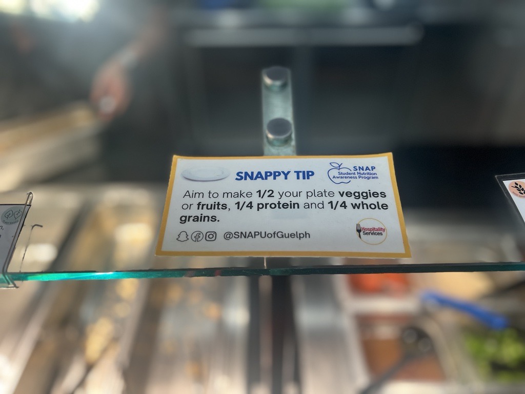 "SNAPPY Tip" posted at a dining hall. Reads: Aim to make 1/2 your plate veggies or fruits, 1/4 protein and 1/4 whole grains with a picture of a plate. 