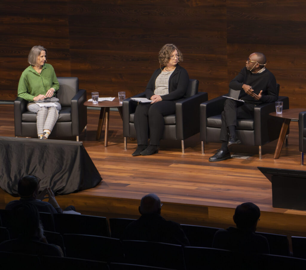 Three panelists sit on stage in black armchairs during a discussion at the Arrell Food Institute event. A large screen behind them shows logos for CCWX and Arrell Food Institute. Audience members are visible in the foreground.